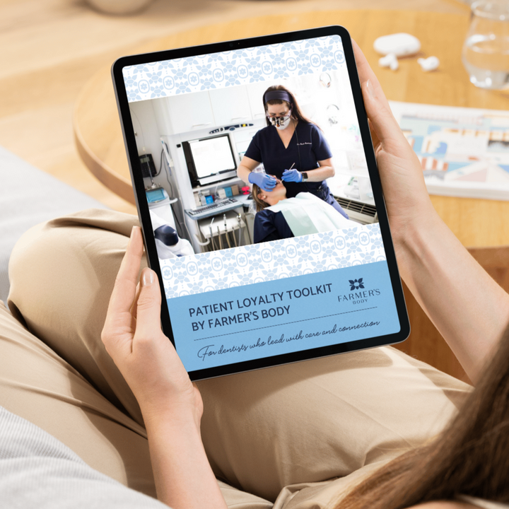Person holding a tablet displaying a 'Patient Loyalty Toolkit' by Farmer's Body on a wooden surface.